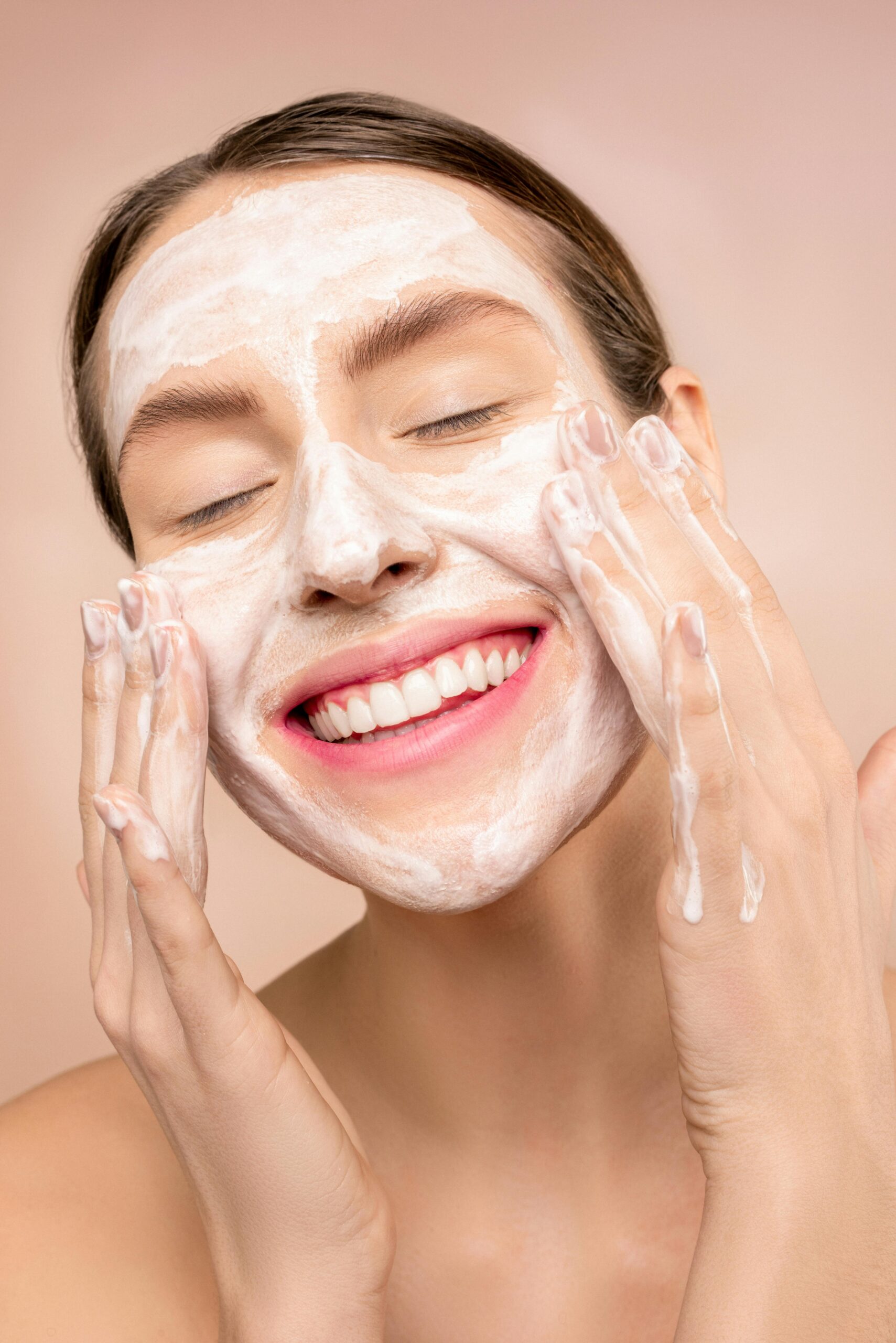 Smiling woman applies facial wash while enjoying her skincare routine, promoting happiness and skin health. dubbel rengöring torr hud.